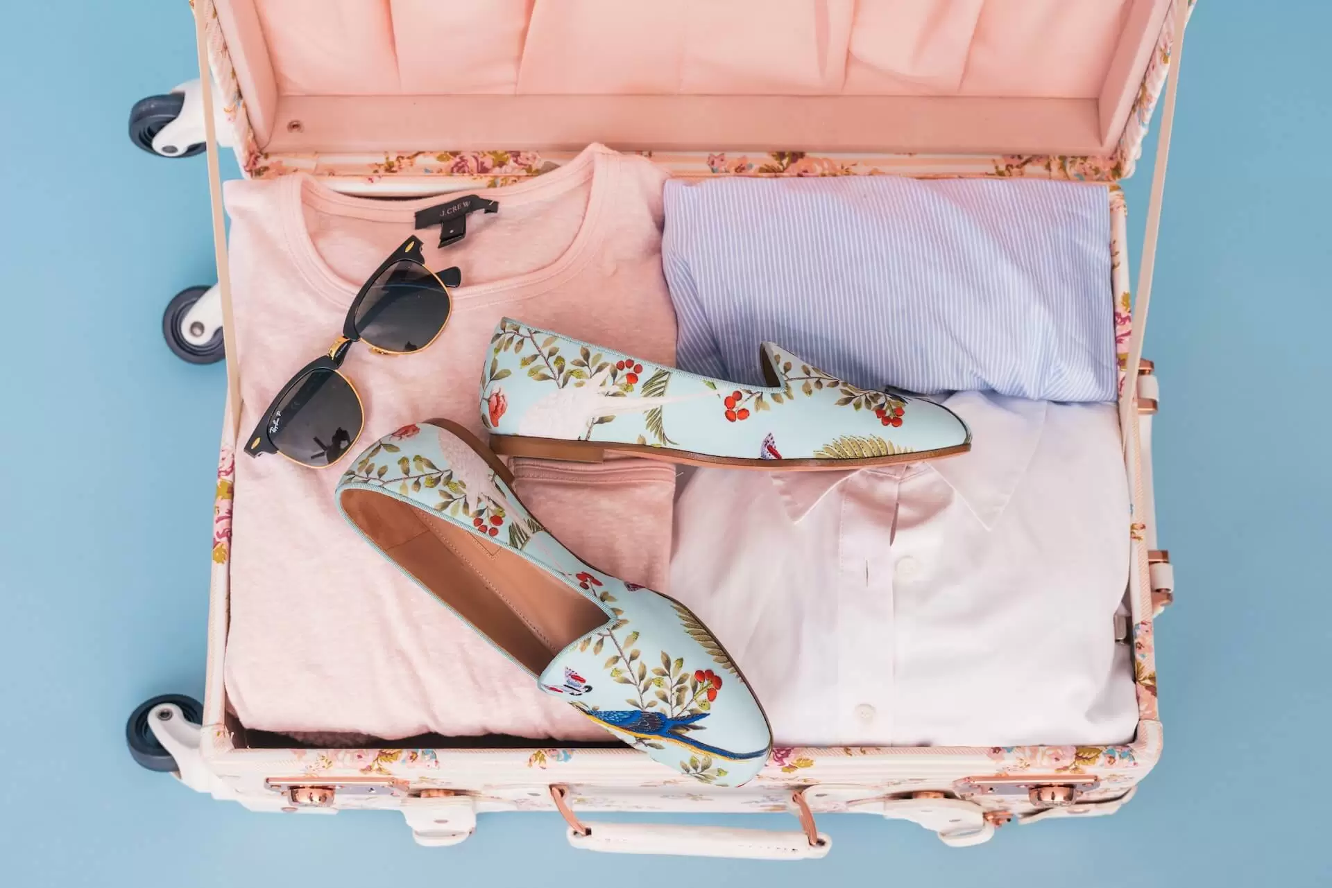 Sunglass, Pair of shoes, and a few cloths in a suitcase.