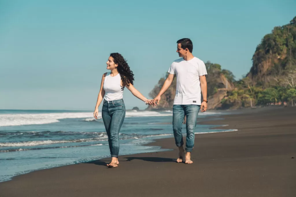 A couple is walking and holding hands on the beach in their romantic vacation.